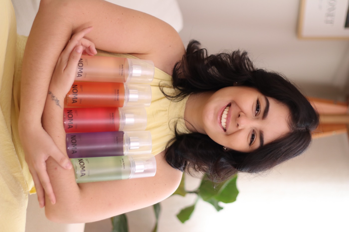 Isabella Natali sorrindo, abraçando os produtos da marca Noma